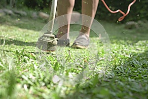 Grass cutting. Man using electric grass trimmer to mow lawn