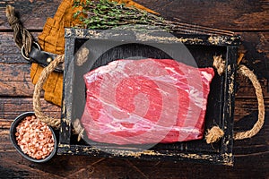 Grass Fed raw flank beef meat steak in wooden tray with herbs. Wooden background. Top view