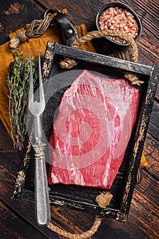 Grass Fed raw flank beef meat steak in wooden tray with herbs. Wooden background. Top view