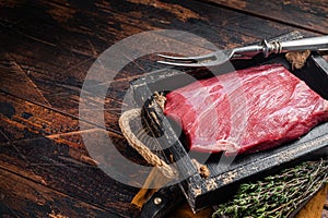 Grass Fed raw flank beef meat steak in wooden tray with herbs. Wooden background. Top view. Copy space