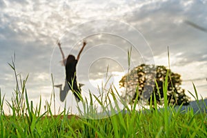 Grass field with blurred background of jumping person and stand alone tree in nature