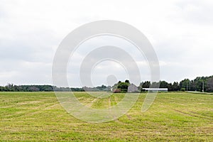 grass field in spring, with barn in the distant background in Kanata, Ottawa