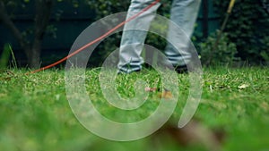 Grass and man with lawnmower. 4K low angle view slow motion shot