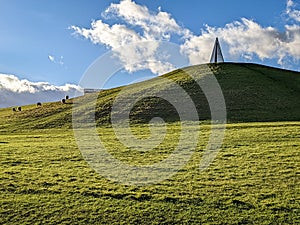 Grass meadow field with green hill under blue cloudy sky, perfect for background