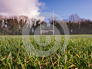 Grass on a pitch in focus, Irish national sport goalpost out of focus in the background. Concept football, rugby, hurling and