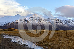 Grass and snow mountains with blue sky in Hofn, Iceland. Winter photo