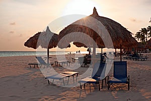 Grass umbrellas at the beach on Aruba at sunset