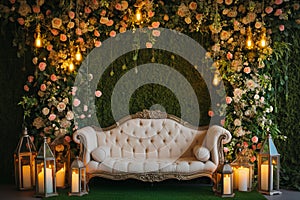 Grass wall wedding backdrop with elegant classic sofa, flowers, candles and lanterns. Luxury decorated blooming wedding photo zone