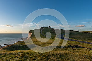 Grassy cliffs, a road that curves around and a footpath to Belle Tout Lighthouse