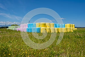 Grassy field with hay bales wrapped in colored polythene