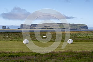 Grassy landscape with mountains and baled hay in meadow near the Black Sand Beach Vik South Iceland