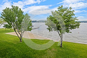 the grassy lawn near the beach is next to a tree and water,  in Lakeport New Hampshire