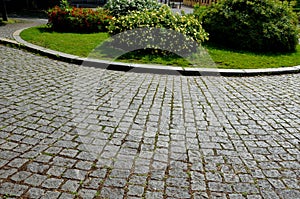 Grassy roundabout with ornamental shrubs. quality road surface of the road with cubes paved like a wind. landscaping in the city