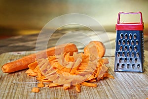 Grated carrot lies in the kitchen, on a vintage wooden cutting board. Unusual mystery and optical illusion