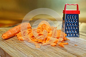 Grated carrot lies on a wooden cutting board on a golden background. Unusual mystery and optical illusion