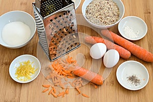 Grated carrots, ground almonds, eggs and spices, baking ingredients on a wooden kitchen board for an Easter carrot cake