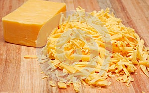 Grated cheddar cheese on wooden board