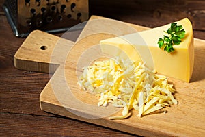 Grated cheese and cheese triangle on wooden cutting board