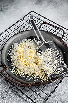 Grated cheese for cooking in a steel tray with grater. White background. Top view