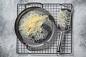 Grated cheese for cooking in a steel tray with grater. White background. Top view