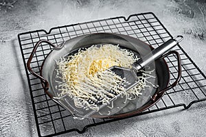 Grated cheese for cooking in a steel tray with grater. White background. Top view