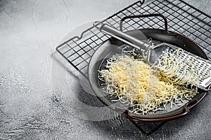 Grated cheese for cooking in a steel tray with grater. White background. Top view. copy space