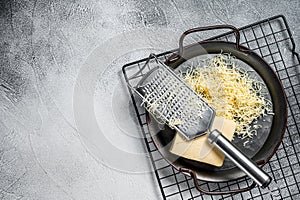 Grated cheese for cooking in a steel tray with grater. White background. Top view. copy space
