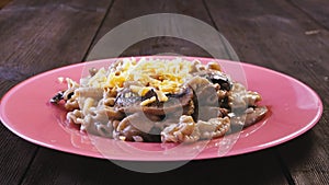 Grated cheese is sprinkled on pasta with mushrooms in a creamy sauce in a plate