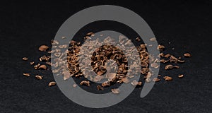 Grated chocolate. Heap of ground chocolate isolated on black background, closeup