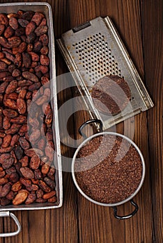 Grated dark chocolate in tin with cocoa beans and solid piece in