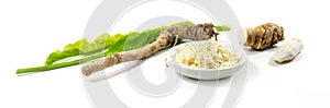 Grated horseradish in a bowl, fresh roots and leaves in panoramic format, isolated on a white background, selected focus, narrow
