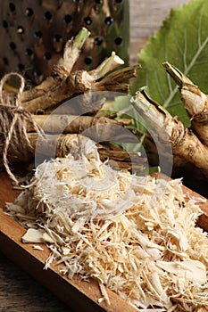 Grated horseradish and roots on table, closeup
