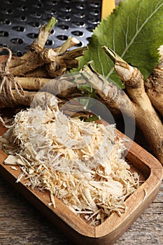 Grated horseradish and roots on wooden table, above view