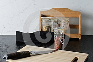 Grated hot red pepper in a glass jar with a cutting board and a knife