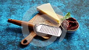 Grated parmesan cheese and metal classic grater placed on wooden cutting board