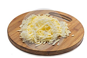 Grated yellow cheese on the wooden cutting board