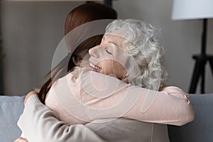 Grateful elderly grandmother pensioner hold in arms adult granddaughter