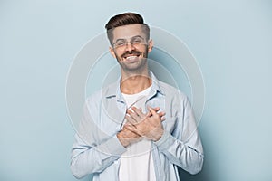 Grateful guy in glasses put hands on chest studio shot