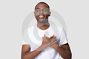 Grateful happy african man holding hands on chest feeling appreciation photo