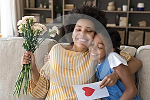 Grateful happy young african american mother cuddling daughter.