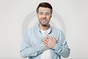 Grateful millennial guy folded hand on chest near heart.