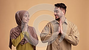 Grateful Muslim Couple Holding Hands In Prayer Gesture, Beige Background
