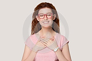Grateful young redhead woman with hands at chest feel thankful
