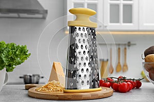 Grater, cheese and vegetables on table in kitchen