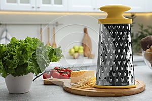 Grater, cheese and vegetables on table in kitchen