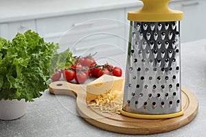 Grater, cheese and vegetables on table in kitchen