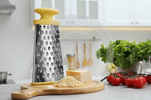 Grater, cheese and vegetables on table in kitchen