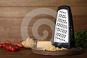 Grater, cheese and vegetables on wooden table. Space for text