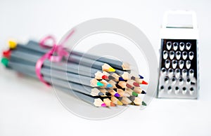 Grater with colored pencils on a white background