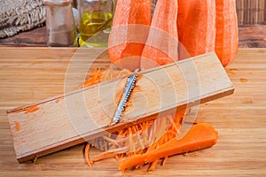 Grater on pile of grated carrots against the whole carrots